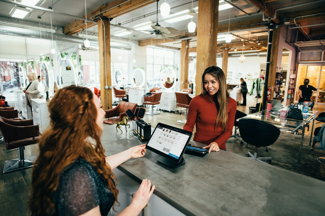 A customer at a counter paying for a shipment on a tablet